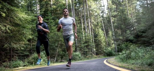 Kobieta i mężczyzna biegają po leśnej drodze.