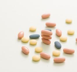 Podłużne i okrągłe, kolorowe tabletki na neutralnym tle.