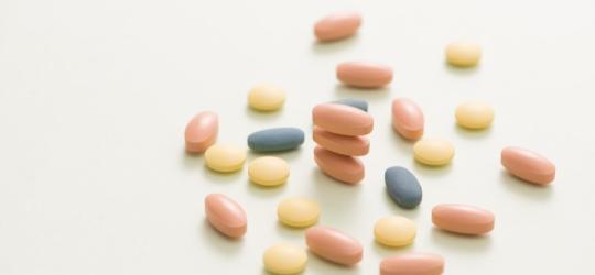 Podłużne i okrągłe, kolorowe tabletki na neutralnym tle.