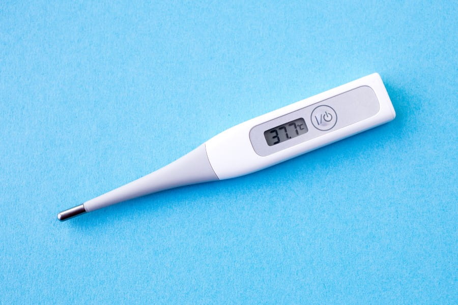 Termometr pokazujący temperaturę 37,7 st. C, wskazującą na stan podgorączkowy.