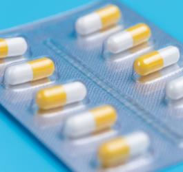 Biał-żółte kapsułki w blistrze na niebieskim tle.