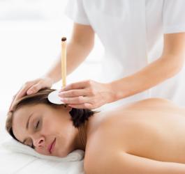 Kobieta ma wykonywany zabieg świecowania uszu.