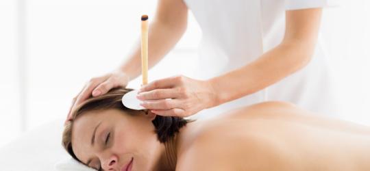 Kobieta ma wykonywany zabieg świecowania uszu.