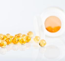 Kapsułki z symetykonem rozsypane obok buteleczki.