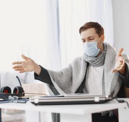 Mężczyzna z maseczce siedzi w biurze.