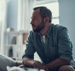 Dorosły mężczyzna siedzi zmartwiony, zmaga się z syndromem DDA.