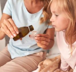 Mama podaje dziecku syrop na kaszel.