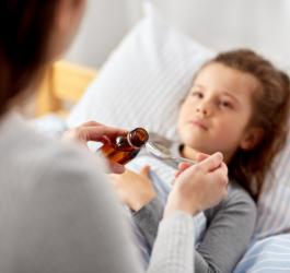 Mama podaje córce syrop na kaszel dla dzieci.