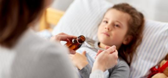Mama podaje córce syrop na kaszel dla dzieci.
