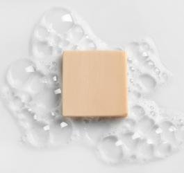 Kostka szarego mydła, które zostało lekko spienione.