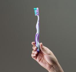 Osoba trzyma w dłoni manualną szczoteczkę do zębów.