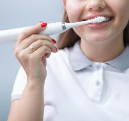 Kobieta korzysta ze szczoteczki sonicznej.