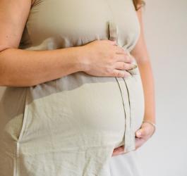 Kobieta w zaawansowanej ciąży trzyma się za ciążowy brzuszek.