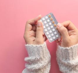 Kobieta trzyma w dłoniach blister tabletek antykoncepcyjnych.