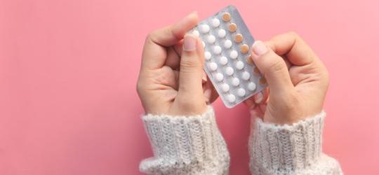 Kobieta trzyma w dłoniach blister tabletek antykoncepcyjnych.