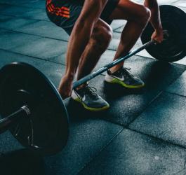 Mężczyzna próbuje podnieść sztangę w martwym ciągu.