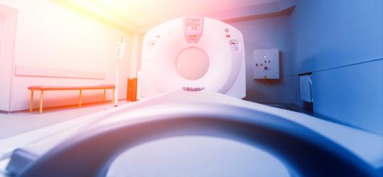 Tomograf komputerowy z perspektywy pacjenta leżącego na stole tomografu.