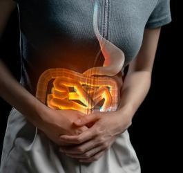 Kobieta trzyma się za bolący brzuch z powodu uchyłków jelita grubego.