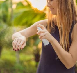 Kobieta używa repelentu w sprayu, aby chronić się m.in. przed ugryzieniem meszki.