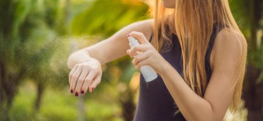 Kobieta używa repelentu w sprayu, aby chronić się m.in. przed ugryzieniem meszki.