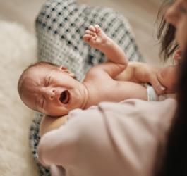 Mama trzyma na rękach noworodka, który płacze.