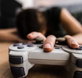 Przemęczony gracz sięgający po kontroler do konsoli.