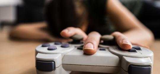 Przemęczony gracz sięgający po kontroler do konsoli.