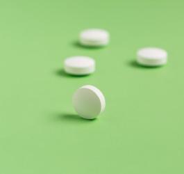 Białe tabletki na zielonym tle.