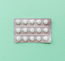 Blister tabletek z warfaryną na zielonym tle.