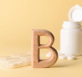 Buteleczka zawierająca tabletki z witaminą B2. Obok drewniana literka B i kasetka na leki.