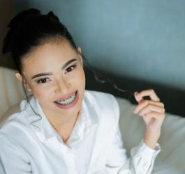 Uśmiechnięta dziewczyna z widocznym na zębach aparatem ortodontycznym.