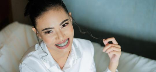 Uśmiechnięta dziewczyna z widocznym na zębach aparatem ortodontycznym.