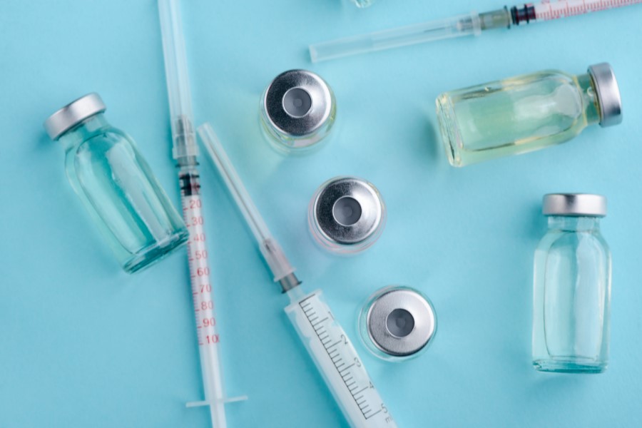 Fiolki i strzykawki na turkusowym tle.