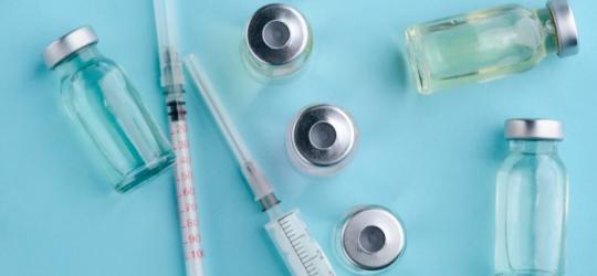 Fiolki i strzykawki na turkusowym tle.