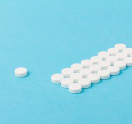 Białe tabletki ułożone równo na niebieskim tle.