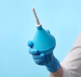 Osoba trzyma w dłoni gruszkę z kanką do przeprowadzania lewatywy.