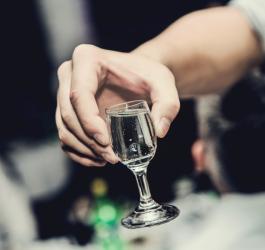 Mężczyzna trzyma w dłoni kieliszek mocnego alkoholu.