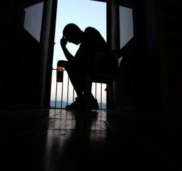 Zmartwiony mężczyzna z butelką piwa siedzi na balkonie