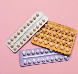 Kolorowe blistry tabletek na różowym tle.