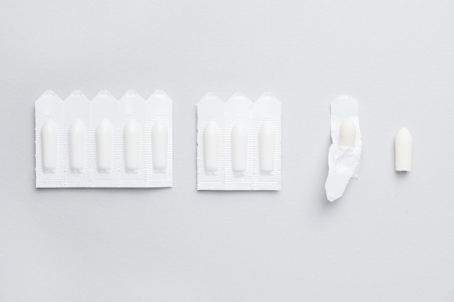 Czopki w blistrze i rozpakowane na neutralnym tle.