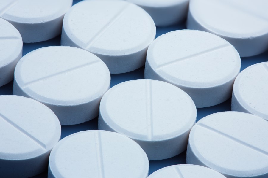 Zbliżenie na białe, okrągłe tabletki z podziałką na środku.