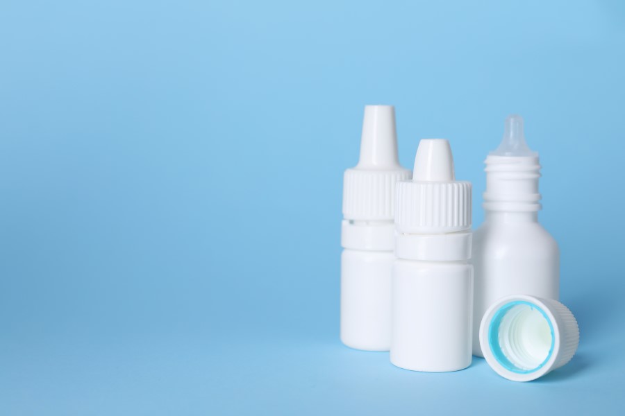 Buteleczki kropli do oczu na błękitnym tle.