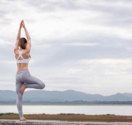 Kobieta w stroju sportowym ćwiczy jogę na świeżym powietrzu.
