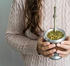 Kobieta trzyma w dłoniach matero wypełnione yerba mate. Będzie pić napar przez bombillę.