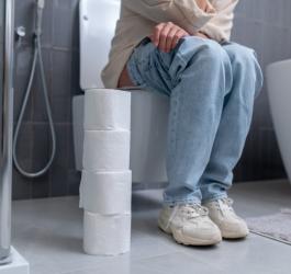 Kobieta siedzi na toalecie, cierpi na zaparcia.