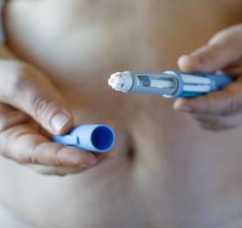 Kobieta trzyma w rękach zastrzyk na odchudzanie.