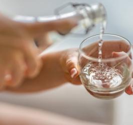 Kobieta nalewa sobie wodę do szklanki.