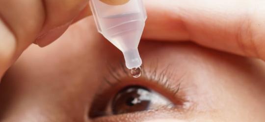 Osoba stosuje krople nawilżające na zespół suchego oka.