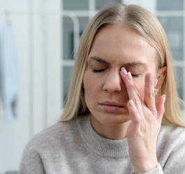 Kobieta pociera dłonią powiekę, cierpi na zespół suchego oka.