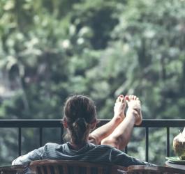 Młoda kobieta siedzi na balkonie i podziwia otaczającą przyrodę.